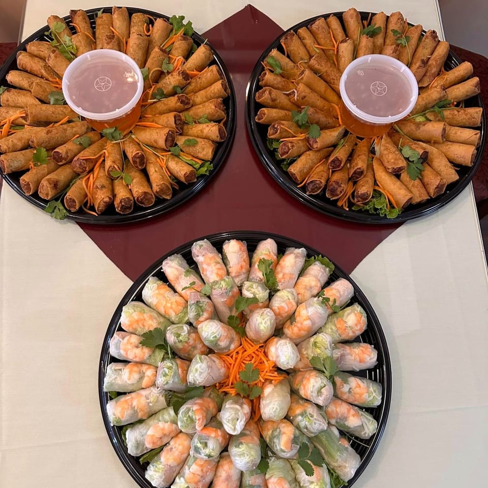 Three platters of vPho Vietnamese spring rolls and fried egg rolls with dipping sauce.