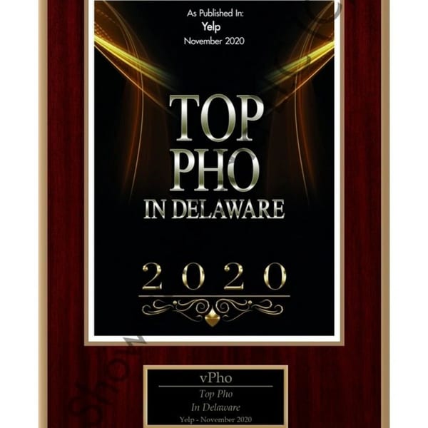 A wooden plaque with a gold and black award for "Top Pho in Delaware 2020" from Yelp.